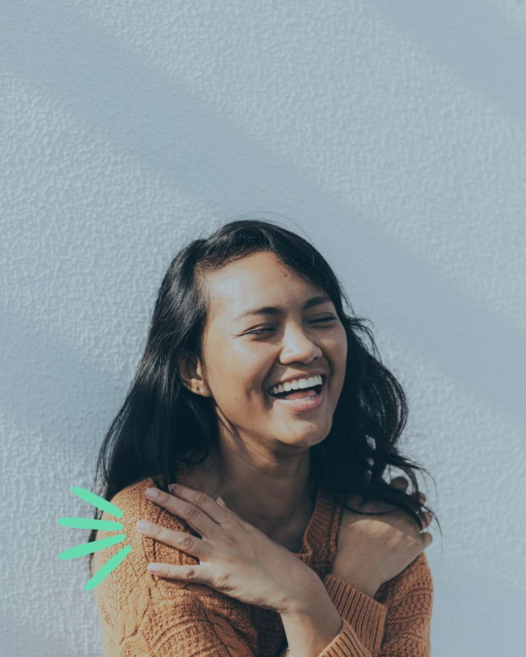 woman smiling and laughing while hugging herself, she has benefited from mental health services