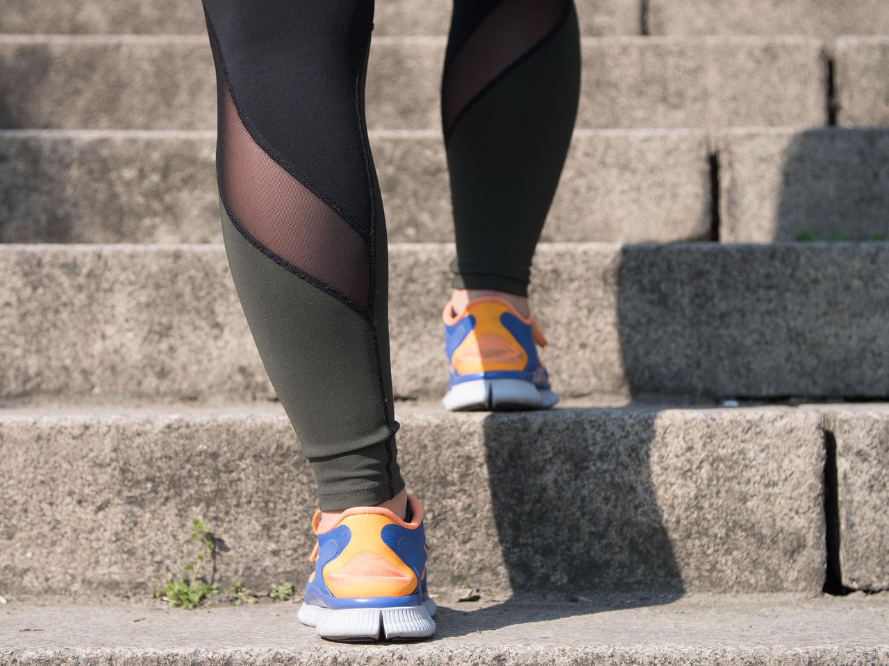 legging-clad legs sporting brightly colored tennis shoes walking up stone stairs
